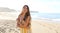 Shot of a beautiful brazilian woman hugging herself while standing on a beach in summer dress