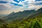 Shot of the breathtaking mountains covered in forests gleaming under the cloudy sky