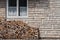 Shot of a brick house wall with lots of chopped wood under its window.