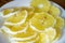 Shot of bright, yellow and sour lemon slices with seeds on white plate in the middle of table