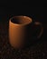 Shot of a brown cup in scattered roasted coffee beans isolated on a black background