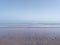 A shot of a calm spring low tide lapping onto a sandy shore beneath a pale blue sky, Dawlish, Devon, UK