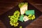 Shot of cheese and green grapes on black slate cheeseboard on wooden table