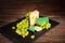 Shot of cheese and green grapes on black slate cheeseboard on wooden table