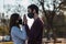 Shot of a couple with masks holding hands in a park - the new normal concept