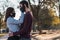 Shot of a couple with masks hugging each other in a park - the new normal concept