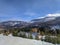 Shot of cozy countryside cottages, scenic nature in winter with snowy mountains in the background