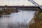 A shot of the Cumberland River flowing under a metal bridge with cars and trucks driving along the bridge