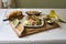 Shot of a delicious panini with salads, avocado on a wooden board on a table with a white fabric