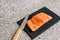 Shot of a delicious piece of salmon on a black board next to a knife