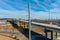 A shot of a freeway filled with cars and Semi trucks and tall power line poles along the highway with yellow winter grass