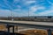 A shot of a freeway filled with cars and Semi trucks and tall power line poles along the highway with yellow winter grass