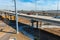 A shot of a freeway filled with cars and Semi trucks and tall power line poles along the highway with yellow winter grass