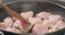 Shot of frying turkey fillet pieces on nonstick pan and moving them with wood spatula