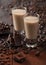 Shot glasses of Irish cream baileys liqueur with coffee beans and powder with dark chocolate on dark wood background