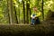 Shot of happy girl sitting on trunk of large fallen tree in park