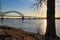 A shot of the Hernando de Soto Bridge over the flowing waters of the Mississippi river with a blue sky at sunset