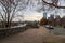 A shot of a long sidewalk with red brick with gorgeous autumn trees and parked cars along the street with powerful clouds