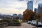 A shot of a long sidewalk with red brick with gorgeous autumn trees and parked cars along the street with powerful clouds