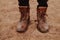 Shot of male stands sandy ground, wears old shaggy shoes, shows footwear. Horizontal view. Man has walk outside. Outdoor