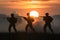 shot Marines in action silhouetted by fiery sunset amidst smoke