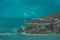 Shot of massive rocks on the shore with turquoise seascape on the background