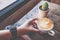 Shot of men`s hand touching a cup of hot milk coffee Latte coffee or Cappuccino coffee on the wooden table in coffee shop.