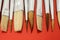 Shot of numerous types of paintbrushes laying on a red surface