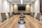 Shot of an office interior with long table, TV, comfortable chairs, projector, lighting, glass door