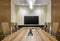 Shot of an office interior with long table, TV, comfortable chairs, projector, lighting, glass door