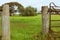 Shot of old gates to a farm with trees and a grassy field