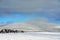 Shot of picturesque winter scenery with a cloudscape, snow-covered landscape, trees, and hills