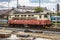 A shot of a red and cream train passing over railway tracks going parallel to the city