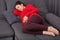 Shot of restful pregnant woman keeps hand on tummy, wears casual clothes, lies on comfortable sofa, going to take nap, rests at