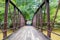 A shot of a rust colored iron bridge covered in fallen leaves over the brown waters of the Chattahoochee silky brown river