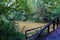 A shot of a rust colored iron bridge covered in fallen leaves over the brown waters of the Chattahoochee silky brown river