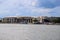 A shot of the Savannah convention center with boats in the water, lush green trees on the banks of the river with blue sky