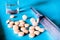 Shot showing a glass ampoule, bottle, tablets, syringe, on blue background, shows the various medicines and treatments