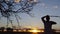 A shot of a silhouetted man whipping a tree