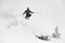 Shot of skier masterfully jumping in the air over a snow-covered mountain slope. Freeride skiing concept