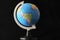 Shot of a small replica of the globe on a stand with a black background