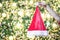 Shot of someone hand pinching Santa Claus hat with beautiful decorative Christmas light bokeh background.