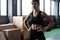 Shot of strong woman standing in crossfit gym and looking away. Confident fitness female model in sportswear.