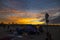 A shot of a stunning orange and yellow sunset with colorful homeless encampment on the beach with silky brown sand