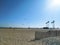 A shot of a sunny day at the beach with people flying kites and blue sky