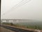 A shot taken from inside of a train. A view of a bridge covered in fog, Delhi India