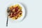 Shot on a white background. No isolation. White plate in it pasta and a piece of meat and a fork