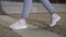 Shot of woman feets in sneakers walking on tile road. Urban Environment