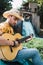 Shot of young adult wearing a cowboy hat playing the guitar in a rural landscape while enjoying his free time