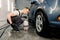 Shot of young Caucasian man in working clothes, car wash employee, washing the car dirty rim under high pressure water